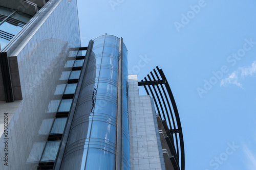Fragment of a modern high-rise building of glass and concrete against a blue sky