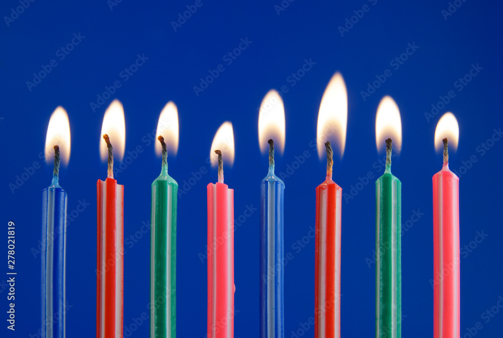 Burning colorful candles on blue background Burning colorful candles on blue background