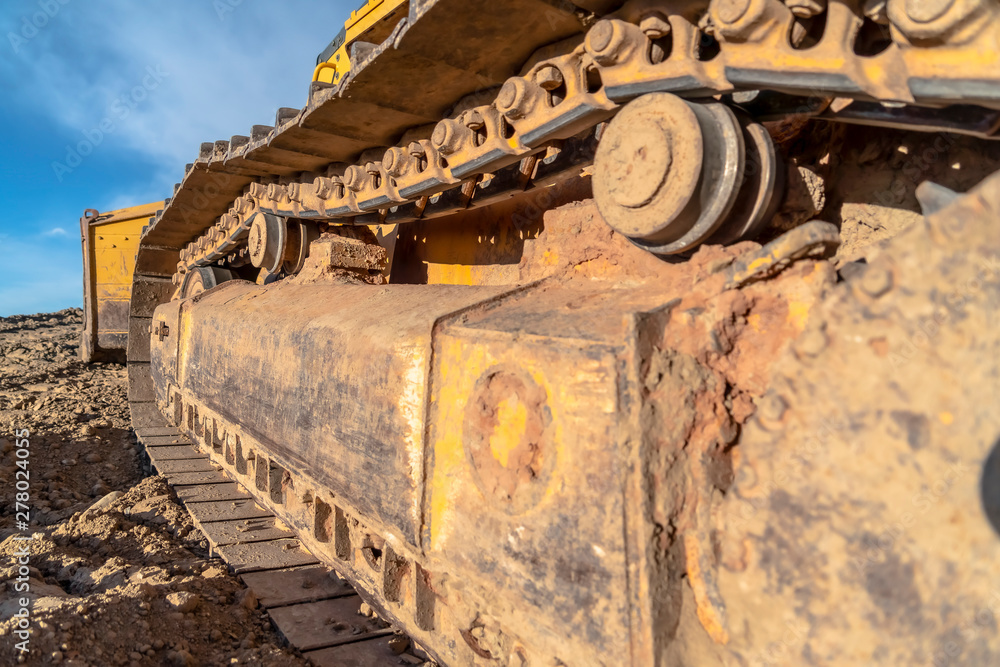 Excavator with close up of the dirty metal track frame and grouser pad Excavator with close up of the dirty metal track frame and grouser pad
