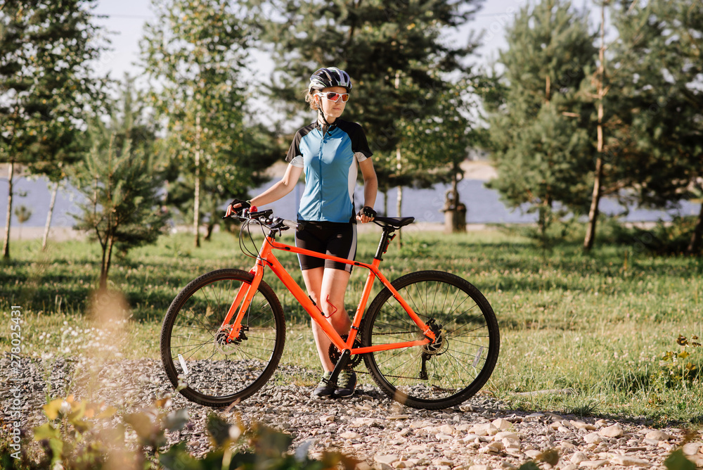 Young pretty woman holding bicycle outdoors at the park