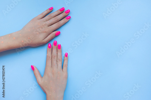 Stylish trendy female manicure. Beautiful neon plastick pink nails on blue background. Nail polish. Art manicure. Modern style.