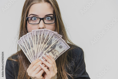 Happy excited young business woman is showing a pile of money, isolated on white background. Girl is satisfied by huge amound of bucks. photo