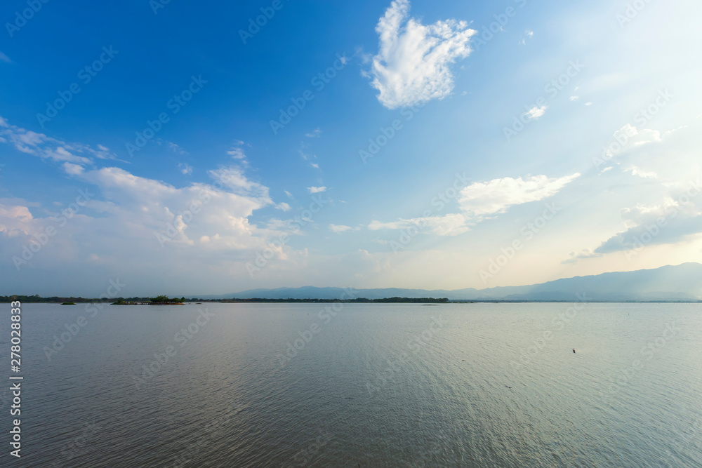 landscape of sunshine on lake or large swamp and mountains and blue dramatic sky with cloud at sunset at 