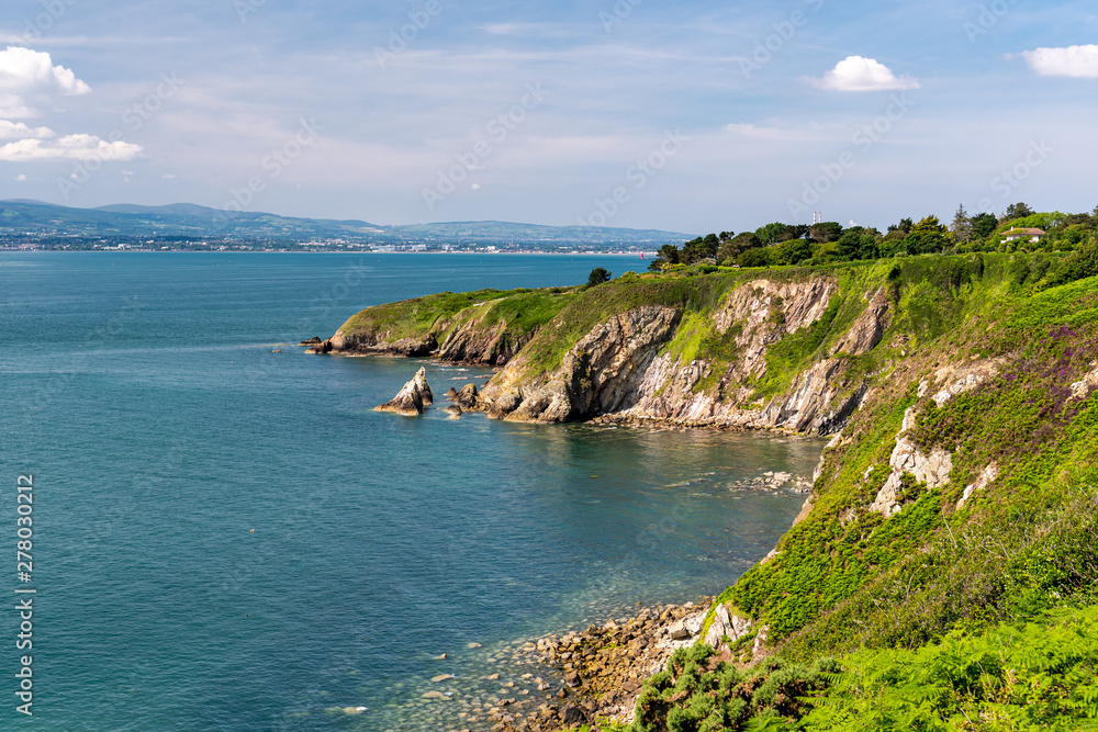 Φωτογραφία View from the popular hiking coastal trail Howth Cliff Walk in county Dublin, Ireland on a sunny summer day with blue Irish Sea clear waters and stunning green cliffs covered in ferns