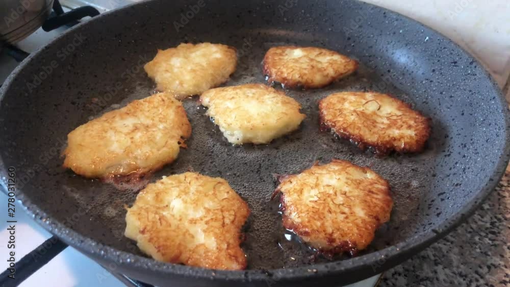 Potato pancakes are fried in vegetable oil in a pan. Cooking potato dishes on the gas stove. The hostess prepares food in the pan. Potato pancakes are fried in vegetable oil in a pan. Cooking potato dishes on the gas stove. The hostess prepares food in the pan.