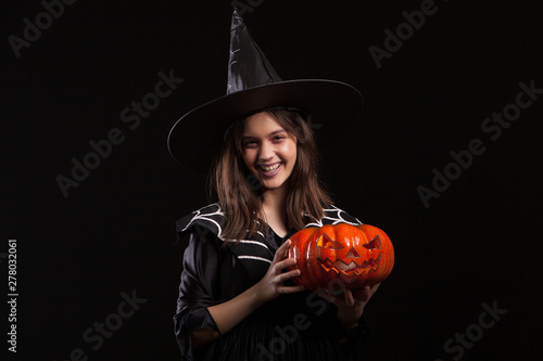 Cute little girl with a evil laugh doing sorcery with a pumpking for halloween