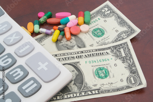 Dollars, calculator and drugs on wooden table, cost of medical help