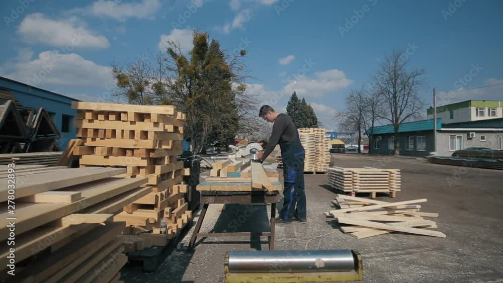 Industrial young carpenter worker operating wood cutting machine. man cuts wooden planks. Industrial young carpenter worker operating wood cutting machine. man cuts wooden planks.