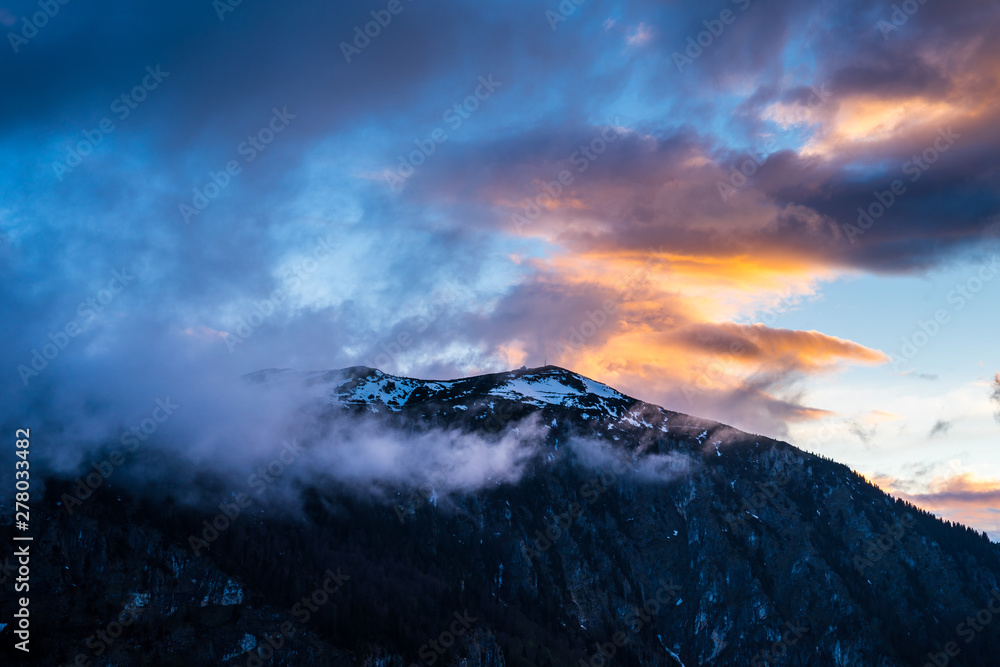 Montenegro, Snow covered peak of durmitor mountains hidden by fog and glowing red clouds in magical dawning atmosphere at sunset on summit of mount curevac in national park near zabljak