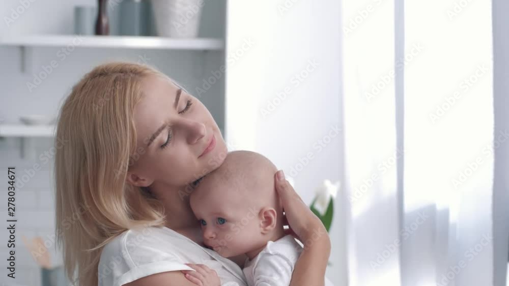 mother love, young parent tenderly holds his newborn girl then hugs and kisses close up on kitchen mother love, young parent tenderly holds his newborn girl then hugs and kisses close up on kitchen