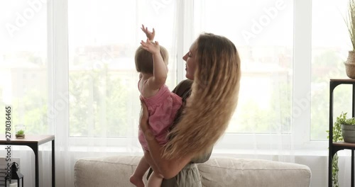 Happy teenage girl dancing with baby sister in her arms photo