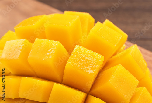 Fresh Mango - Juicy chopped mango cubes on wooden cutting board and rustic timber background. Tropical summer concept. Close up, macro, copy space.