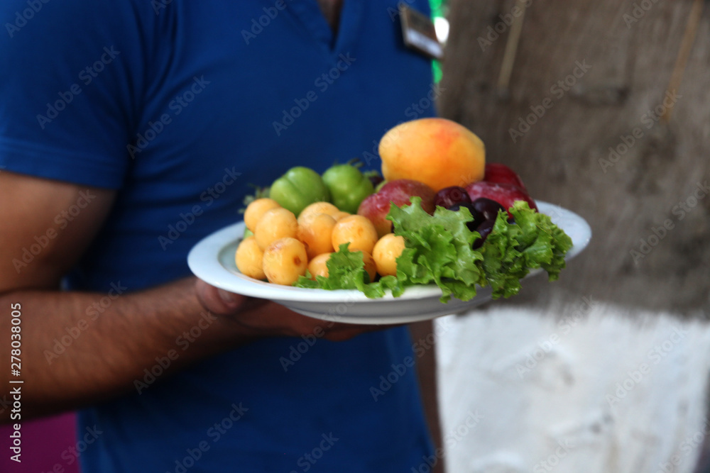 Waiter serving fruits on the plate