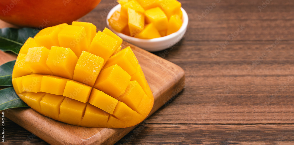 Fresh Mango - Juicy chopped mango cubes on wooden cutting board and rustic timber background. Tropical summer concept. Close up, macro, copy space. Fresh Mango - Juicy chopped mango cubes on wooden cutting board and rustic timber background. Tropical summer concept. Close up, macro, copy space.