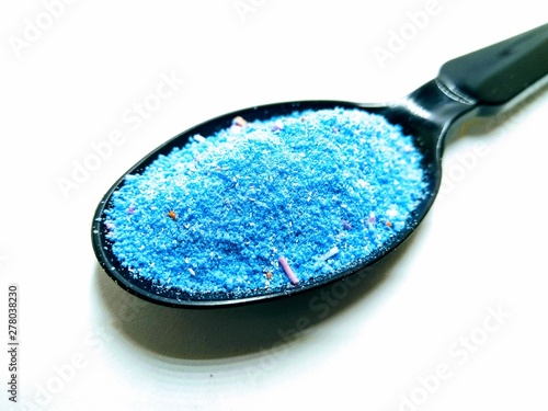 A picture of washing powder on a black spoon