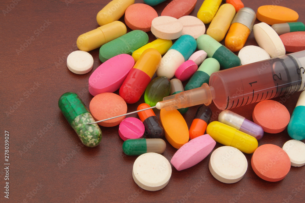 Colorful drugs, pills and syringe on wooden table with room for text, pharmacy and medical concept. Colorful drugs, pills and syringe on wooden table with room for text, pharmacy and medical concept.