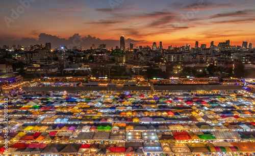 top view of busy Asian street food at railway night market in Thailand with colorful stall and light at night time