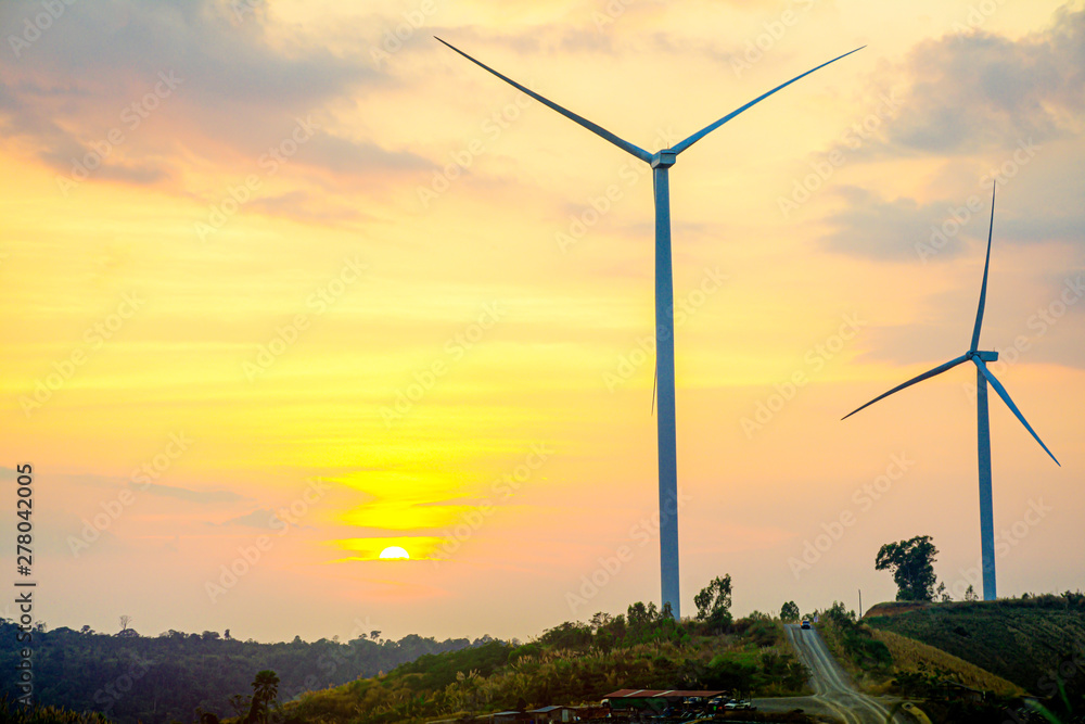 Obraz premium Windmills on the hill with sunset sky, Wind turbine generator to build electricity power in rural area, Electricity power concept