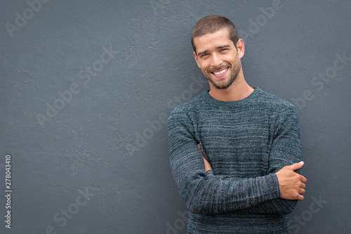 Smiling young man leaning against grey wall