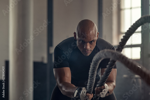 Fotografia Athletic man using battle rope at gym