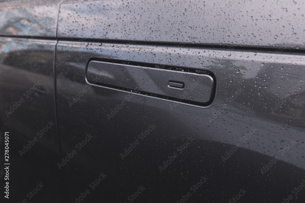 Car door with keyless access on rainy day. Grey car closeup. Modern technologies. Flat door handle. 