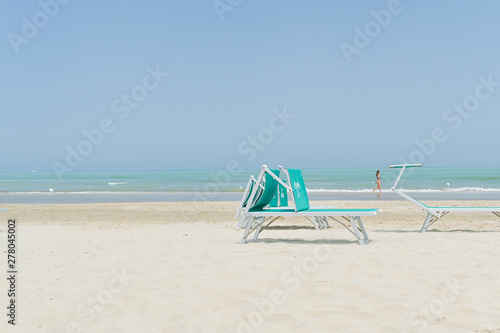 Beach and deck chairs are white. Sand, sea and sky. Quay in the summer. Copy space