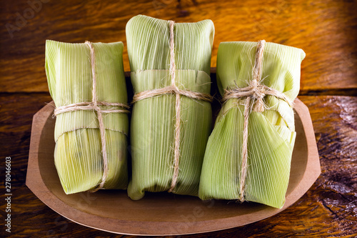 pamonha-Brazilian typical of rural towns. Sweet corn with cheese served in straw. Concept of rural and regional Brazilian food. photo