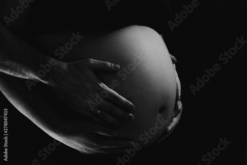 manos de padres sobre tripa de embarazada - blanco y negro