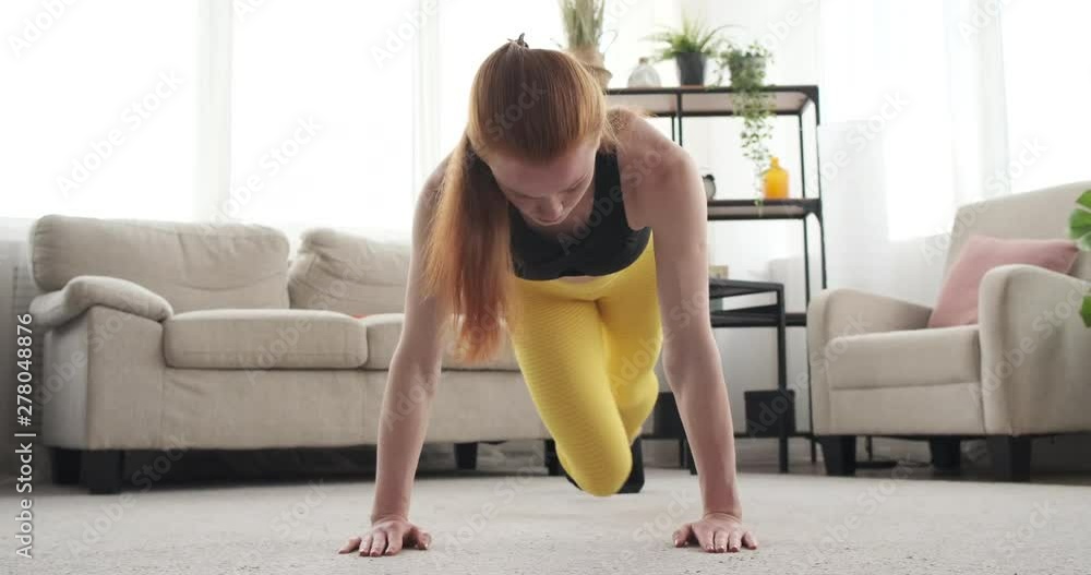 Sportswoman doing alternate knee to elbow plank exercise at home Sportswoman doing alternate knee to elbow plank exercise at home