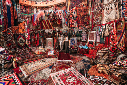 Couple travels the world. Man and woman in the store. Happy couple on vacation. Man and woman in the Eastern country. Gift shop. Persian shop. Tourists in store. Oriental carpet. Follow me