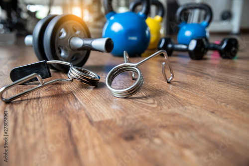 Close up metal tool for hand exercise blurred Ab. rooler wheel, dumbbell and kettlebells in gym. photo