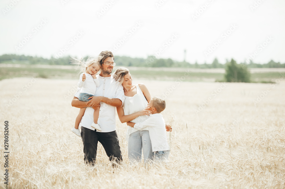 An Happy family of four having fun in the wheat field on sunny summer day. An Happy family of four having fun in the wheat field on sunny summer day.