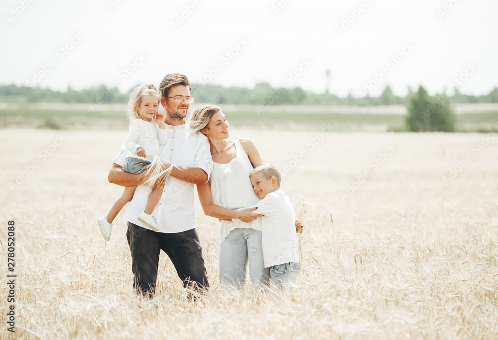 Happy family, father, mom, son and girl in wheat field on summer day.
