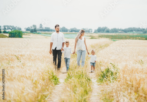 Family of four walking on the field in nature.