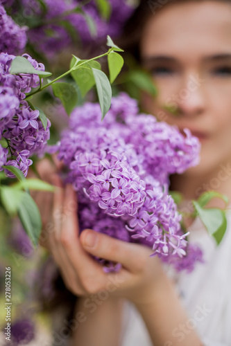 Close-up. Portrait of a beautiful young woman near the blossoming lilac. Spring.