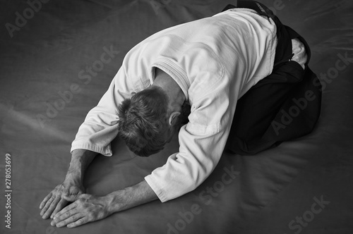 Black and white image of aikido. Athlete in the traditional form of Aikido. White kimano and black hakame. A bow as a sign of respect and welcome. © Uladzimir