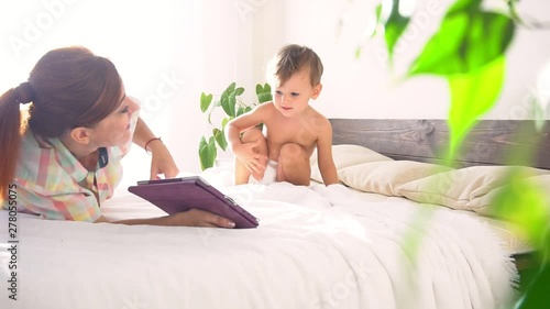 Mom and son watch tablet in bedroom