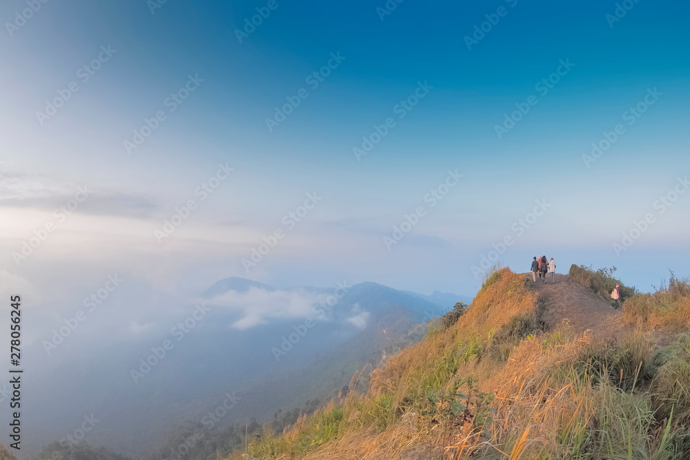 Mountain view of tourists standing on top hill around with mountains, soft mist with cloudy sky background, Phu Chi Fa (Phu Chee Fah), Chiang Rai, northern of Thailand.