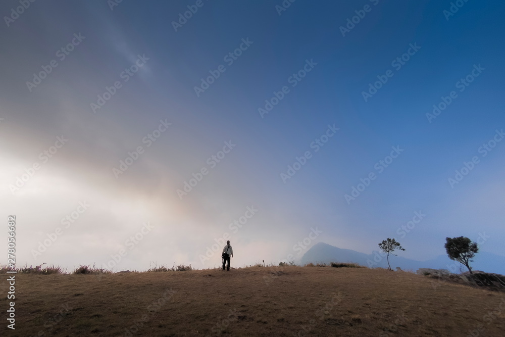Mountain view of a man standing on top hill with cloudy sky background, Phu Chi Fa (Phu Chee Fah), Chiang Rai, Thailand.