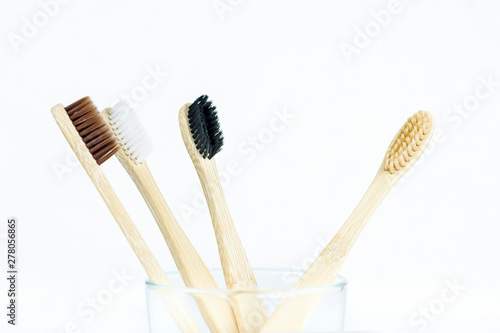 Eco-friendly bamboo toothbrushes in a transparent glass on a white background. Zero waste concept