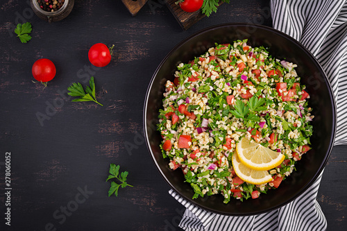 Tabbouleh salad. Traditional middle eastern or arab dish. Levantine vegetarian salad with parsley, mint, bulgur, tomato. Top view photo