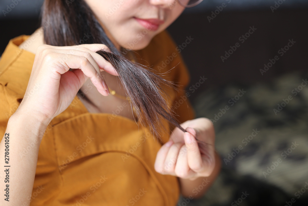 Woman hand holding her long hair with looking at damaged splitting ends of hair care problems Woman hand holding her long hair with looking at damaged splitting ends of hair care problems