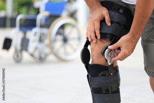 Fotografie Senior man wear knee support brace on leg standing at the road, Medical and heal