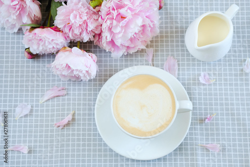 cappuccino with milk on a gray napkin in peonies