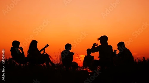 people sitting on the beach with campfire at sunset
