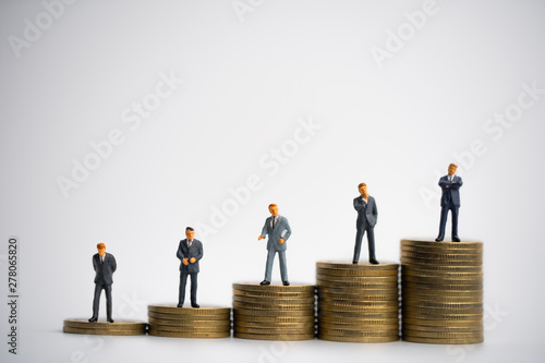 Small businessmans figures standing on tstack of coins. Time is money. Time investment and retirement saving. 401K. Business finance.
