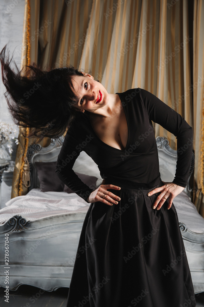 Fashion portrait of young beautiful female model standing in black sexy dress in interior studio. Fashion portrait of young beautiful female model standing in black sexy dress in interior studio.