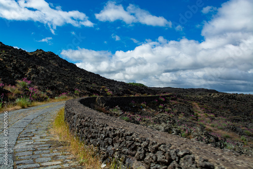 Stone road through black lava fields on slopes of Mount Etna volcano  car access to National Park of Etna  Sicily island  Italy