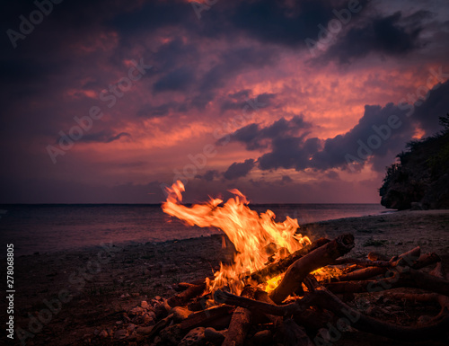 Murais de parede A fantastic sunset at the beach with a bonfire and BBQ on the island of Curacaio