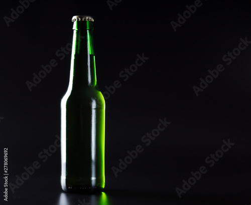 Isolated light green beer bottle on a black background.